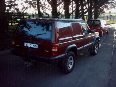 2000 Jeep Cherokee - Maroon Jeep Cherokee van with a license plate reading 98-C-3493 is parked next to another vehicle.