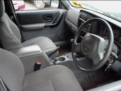 2000 Jeep Cherokee - The interior of a 2000 Jeep Cherokee is visible from the passenger side, showing the dashboard and seats.
