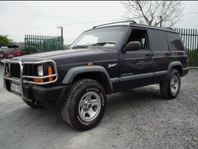 2000 Jeep Cherokee - This Jeep Cherokee is parked on a gravel lot with a metal fence in the background.