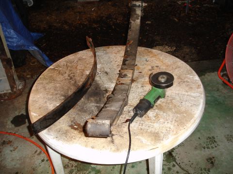 1989 Ford Bronco - A leaf spring and an angle grinder are on a table, suggesting repair or modification work.
