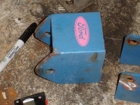 1989 Ford Bronco - A blue metal bracket with a Ford logo is shown, along with a marker and other metal parts.