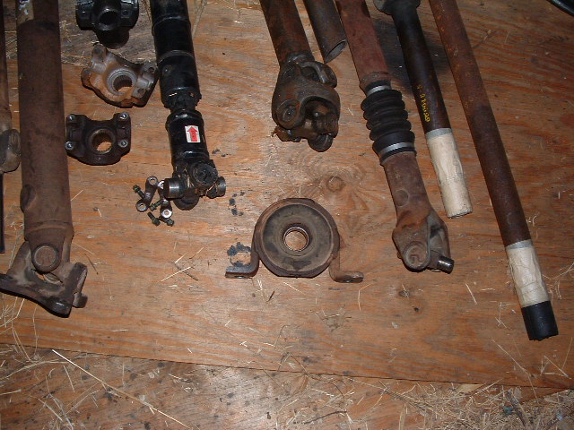 Collection of rusty driveshafts and U-joints on a wooden surface
