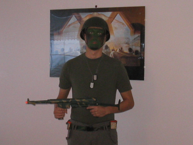 Person in a helmet and face paint holds a toy rifle