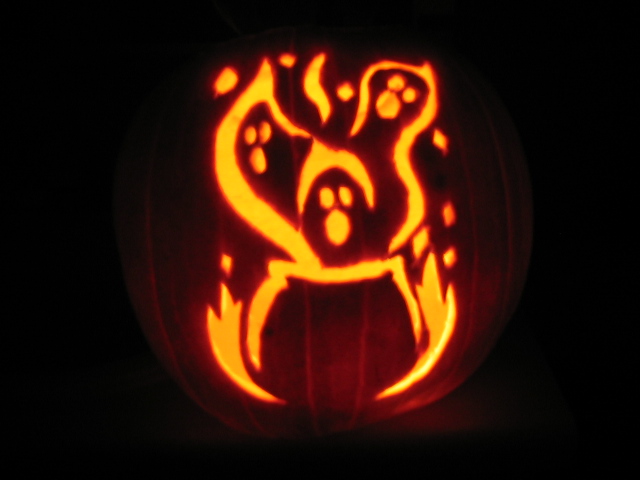 Carved pumpkin with ghost and flame design, lit from within