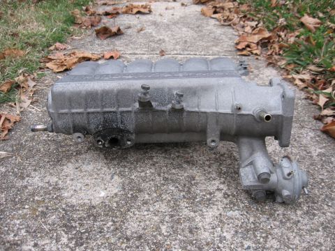 1991 Mitsubishi 3000GT - Intake manifold from a 1991 Mitsubishi 3000GT sits on a concrete surface.