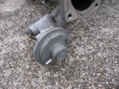 1991 Mitsubishi 3000GT - A close-up view of a vacuum actuator part, marked with 'PC3', resting on a concrete surface.