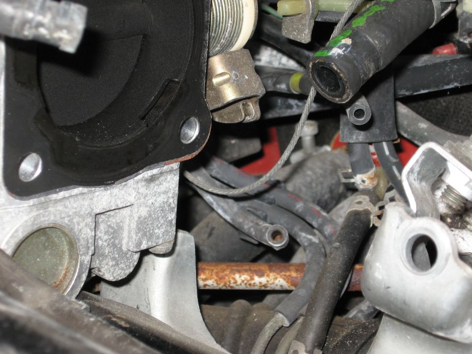 Disconnected throttle body flange and vacuum lines in a grimy engine bay
