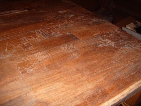 1988 Ford Bronco - This image shows a heavily scratched wooden surface, possibly a table, with some white residue.