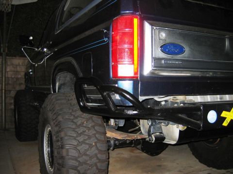 1985 Ford Bronco - Rear view of a 1985 Ford Bronco with custom off-road modifications, including large tires and a heavy-duty bumper.