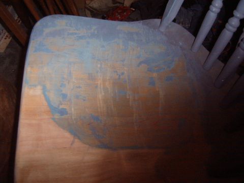 1988 Ford Bronco - The seat of a wooden chair is partially covered in blue paint, revealing the wood grain underneath.