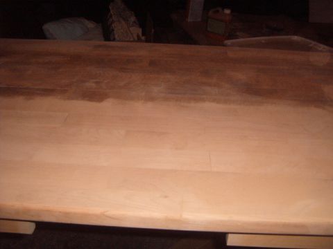 1988 Ford Bronco - A wooden surface shows a transition from stained to unstained wood, with some items in the background.