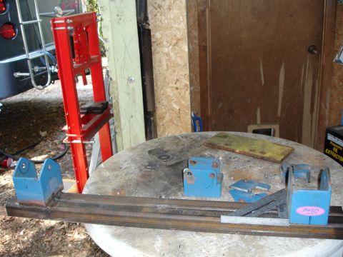 1989 Ford Bronco - Metal fabrication parts are laid out on a workbench, with a red press visible in the background.