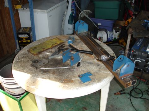1989 Ford Bronco - Metal fabrication parts and tools are laid out on a round table, with a welding machine visible.