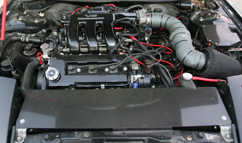 Mazda V6 DOHC 24-valve engine bay with red plug wires and carbon-fiber cover
