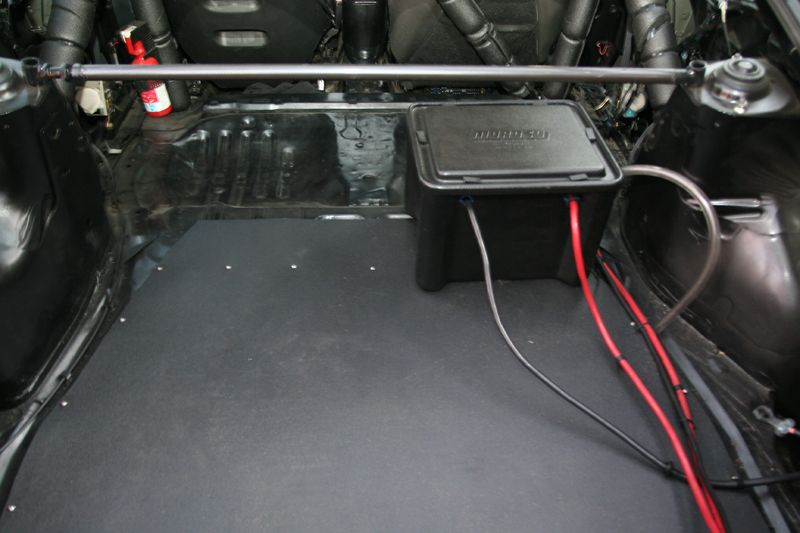 Gutted hatchback trunk with relocated battery in sealed box, heavy cables and rear strut bar