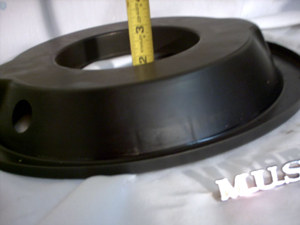 Black air cleaner housing with a yellow Stanley measuring tape inserted into the opening. 'MUS' emblem is visible in the lower right