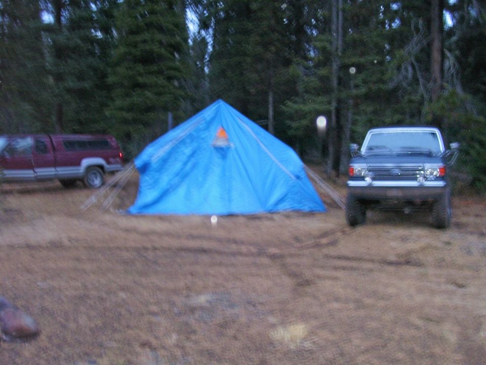 Ford Bronco parked at campsite with blue tent and red pickup truck
