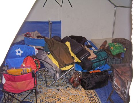 1991 Ford Bronco - Camping gear piled inside a tent, including chairs, bags, and clothing.