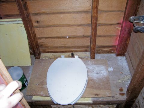 1991 Ford Bronco - A toilet is installed in a rustic attic space, surrounded by wooden beams and unfinished walls.