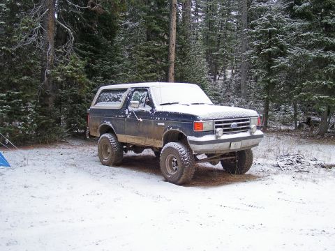 1991 Ford Bronco - A Ford Bronco sits in a snow-covered wooded area, ready for adventure.