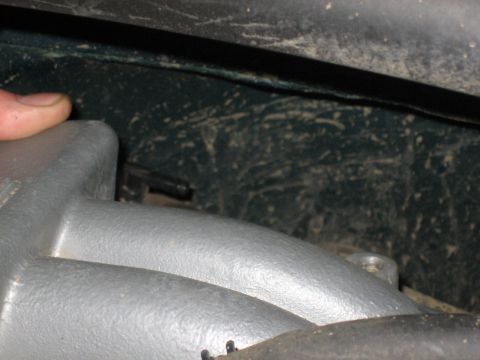 1995 Ford Bronco - A close-up view of an engine's intake manifold, with a finger indicating a small black hose.
