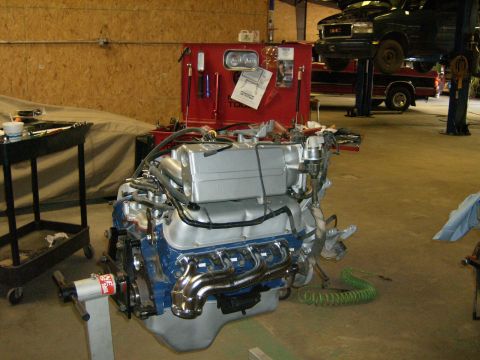 1992 Ford Bronco - A freshly rebuilt Ford V8 engine mounted on an engine stand in a garage, featuring a blue block, silver-painted intake and valve covers, an…