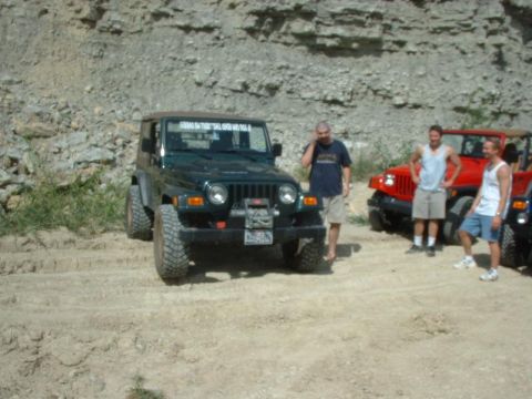 1988 Ford Bronco - A group of people stand near a green Jeep Wrangler and a red Jeep in a rocky, outdoor setting.