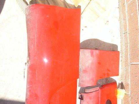 1997 Ford Probe - Red car bumper parts are stacked, showing signs of wear and tear.