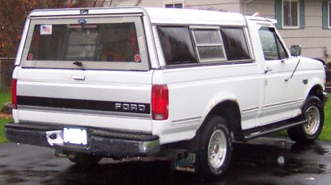 1978 Ford Bronco - White Ford pickup truck with a camper shell, seen from the rear. The body style suggests an early 1980s model.