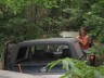 1989 GMC Jimmy - A dark-colored SUV is partially obscured by dense foliage, suggesting it has been stationary for some time.