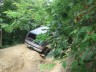 1989 GMC Jimmy - An off-road vehicle navigates a rough, wooded trail.
