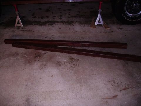 2000 Chevrolet Tahoe - Two rusty metal bars lie on a concrete floor, with a car tire and jack stands in the background.