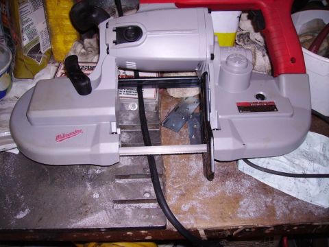 2000 Chevrolet Tahoe - A Milwaukee portable band saw is shown on a workbench, with its blade visible.