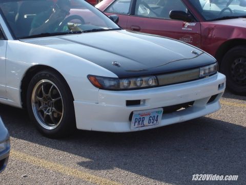 1993 Mazda MX-6 - Front view of a white sports car with a black hood and aftermarket wheels, parked next to another vehicle.