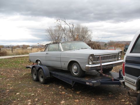 1964 Ford Galaxie - A gray convertible, likely a 1965 model, is seen being transported on a trailer.