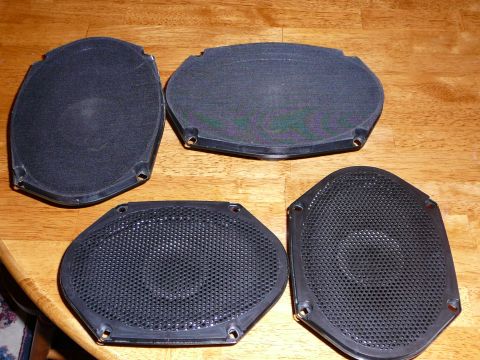 1997 Mercury Grand Marquis - Four car speakers are laid out on a wooden table, likely for installation or replacement.