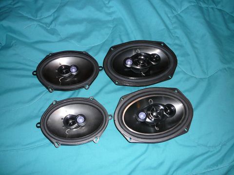 1997 Mercury Grand Marquis - Four aftermarket oval car speakers are laid out on a teal fabric surface.