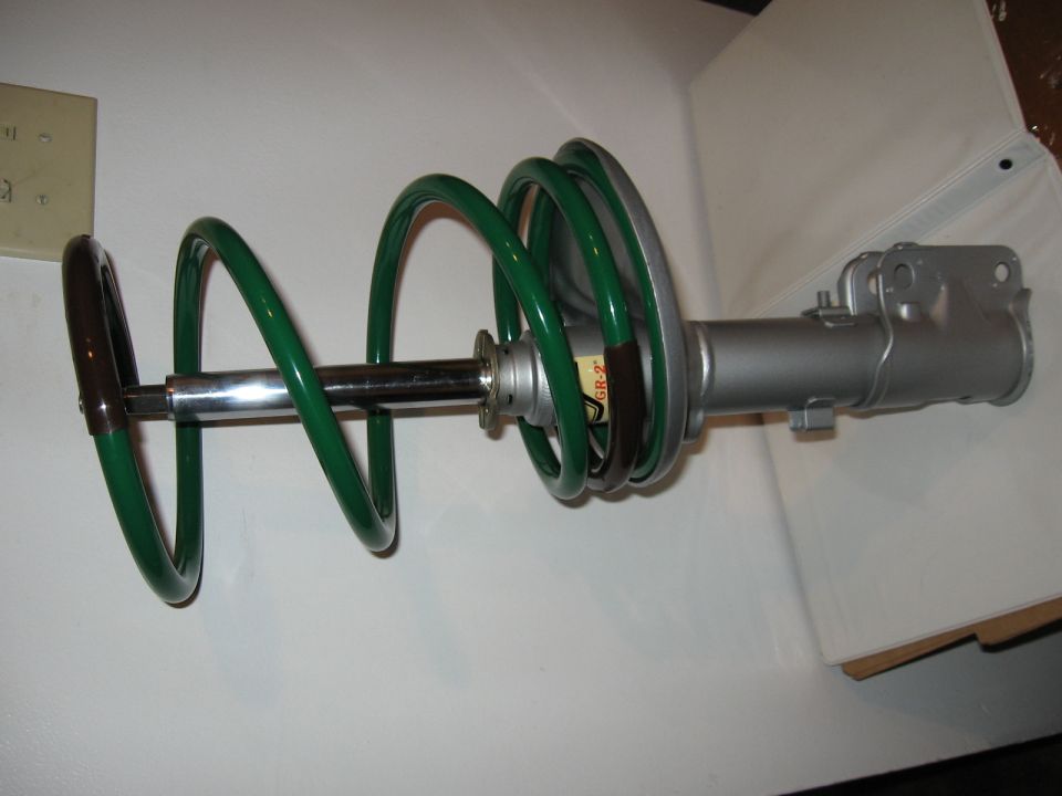 Strut assembly with green lowering spring and silver KYB GR-2 shock body on a white background