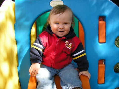1998 Ford Taurus - A smiling baby sits on an orange slide, part of a colorful Little Tikes playground structure.
