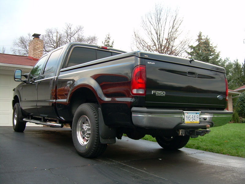 Rear view of a black Ford F-250 long-bed crew cab pickup in a driveway