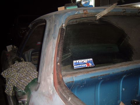 1971 Ford Ranchero - A sticker reading "Ranchero USA" is affixed to the rear window of a blue vehicle, with a plaid cloth visible inside.