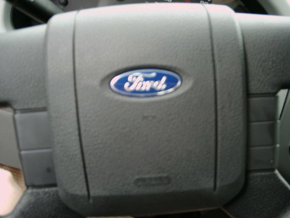 Ford steering wheel with blue oval logo. Part of dashboard visible