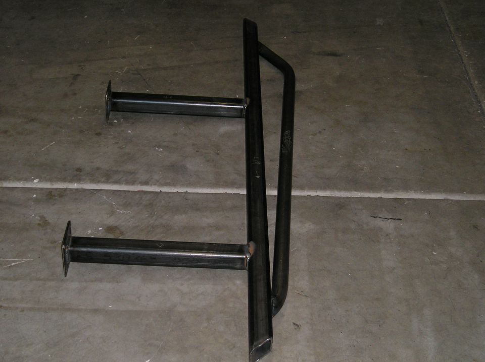 Bare welded steel custom bumper or tire-carrier weldment with mounting arms on concrete