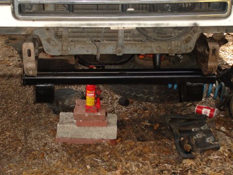 1989 Ford Bronco - Front end of a vehicle is elevated on jack stands, revealing the grille and bumper assembly.