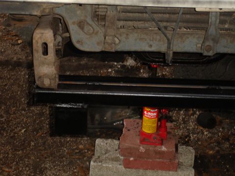 1989 Ford Bronco - Vehicle's front bumper and grille area are visible, supported by a 4-ton hydraulic jack and bricks.