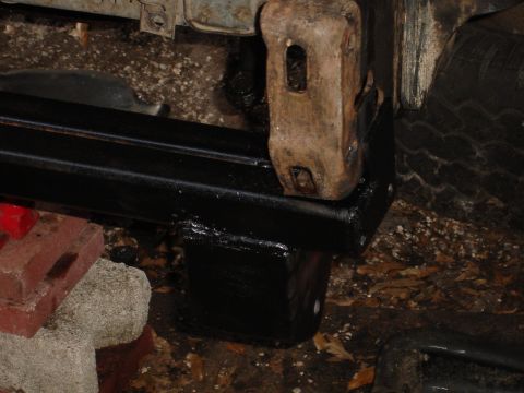 1989 Ford Bronco - Close-up of a rusted metal bracket attached to a black frame, likely part of a vehicle repair.