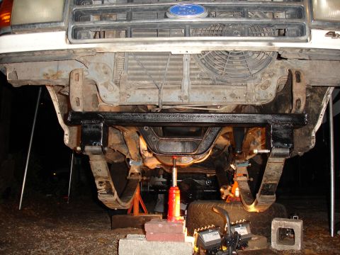 1989 Ford Bronco - The front end of a Ford truck is elevated for maintenance, revealing the suspension and engine cooling fan.