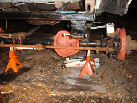 1989 Ford Bronco - The rear axle assembly of a vehicle is supported by jack stands and a floor jack, indicating maintenance or repair work.