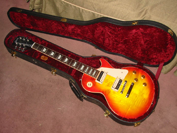 Sunburst electric guitar with white pickguard in a red velvet-lined case