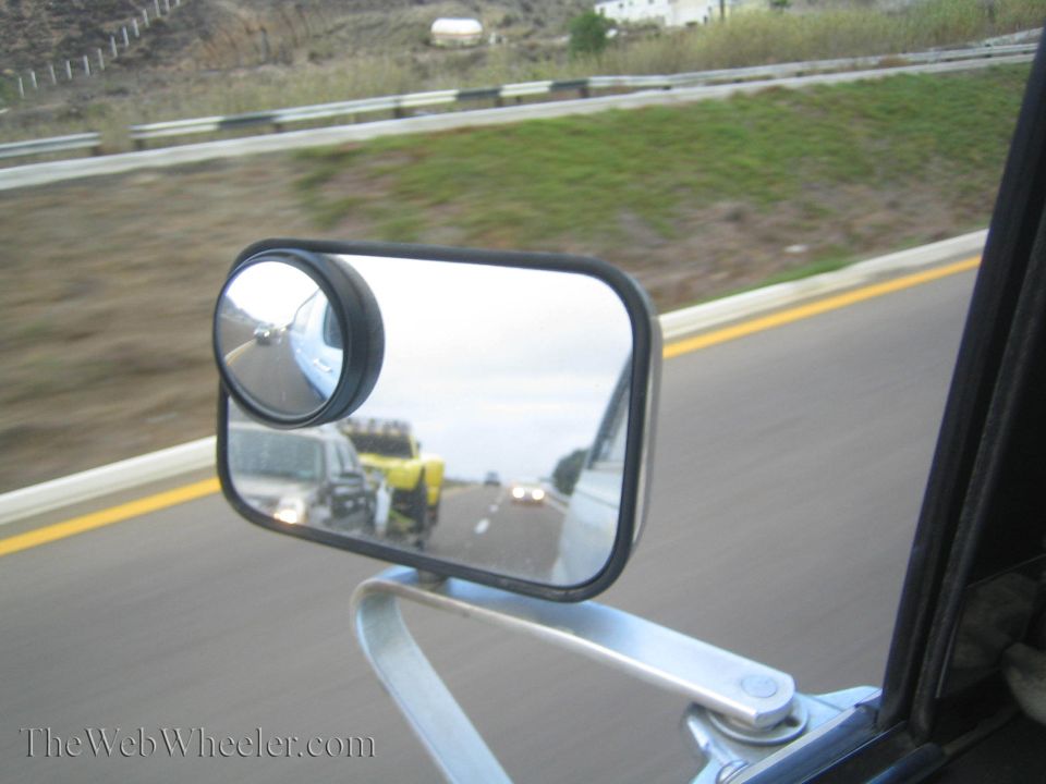 Round convex blind-spot mirror clipped to a vehicle side mirror on a highway